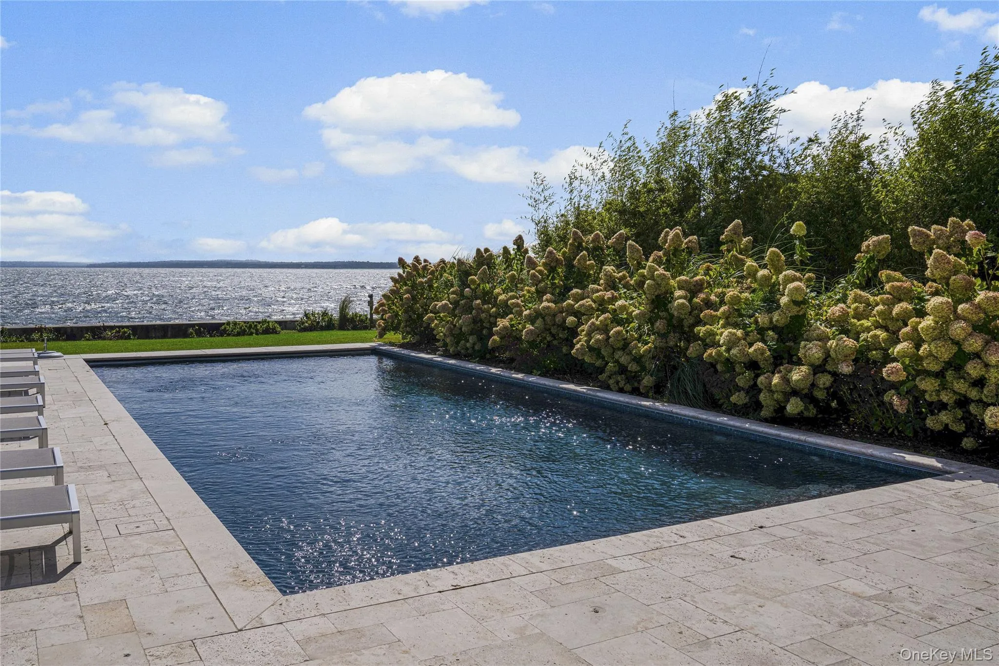 Outdoor pool with a LI Sound water view and a patio Outdoor pool with a LI Sound water view and a patio