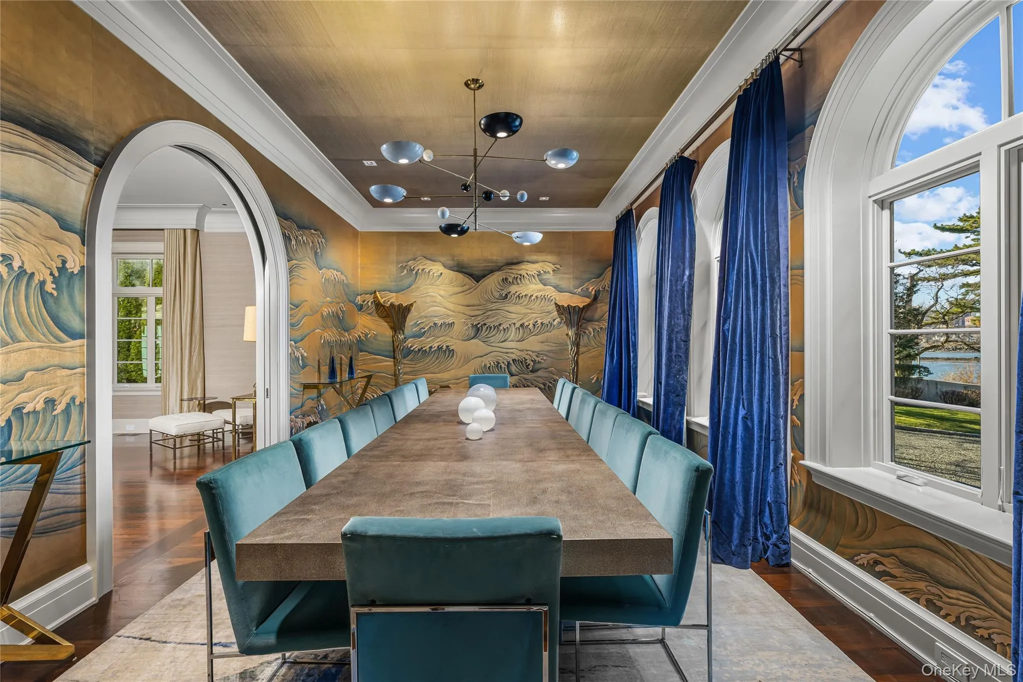 Dining room with arched walkways, dark wood-type flooring, crown molding, a water view, and a chandelier Dining room with arched walkways, dark wood-type flooring, crown molding, a water view, and a chandelier