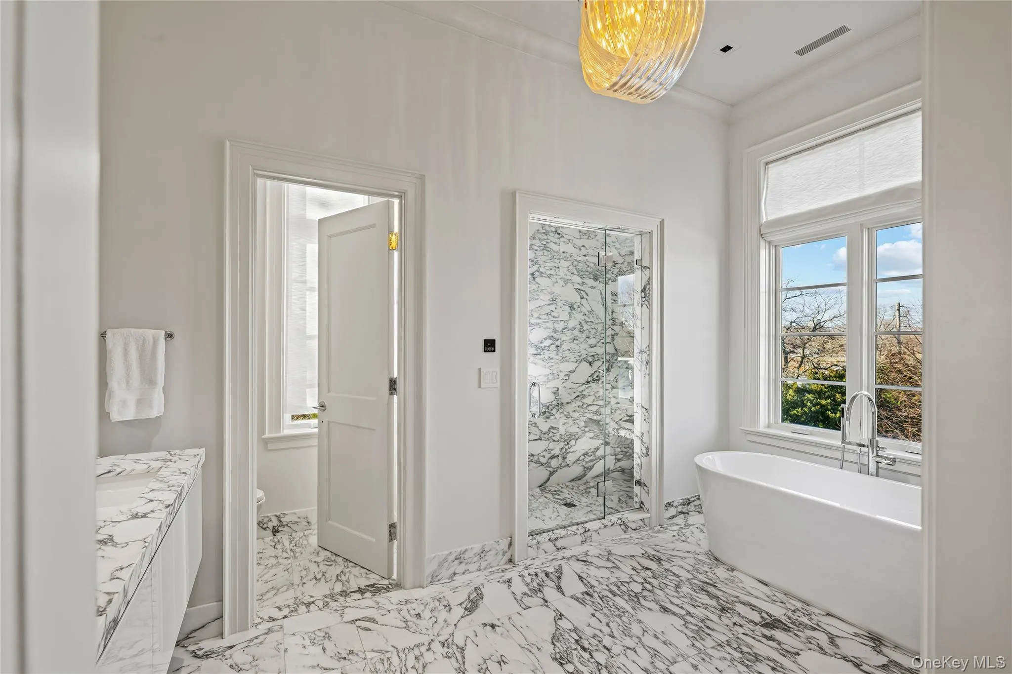 Full bath with a freestanding tub, a marble finish shower, vanity, and light marble finish flooring Full bath with a freestanding tub, a marble finish shower, vanity, and light marble finish flooring