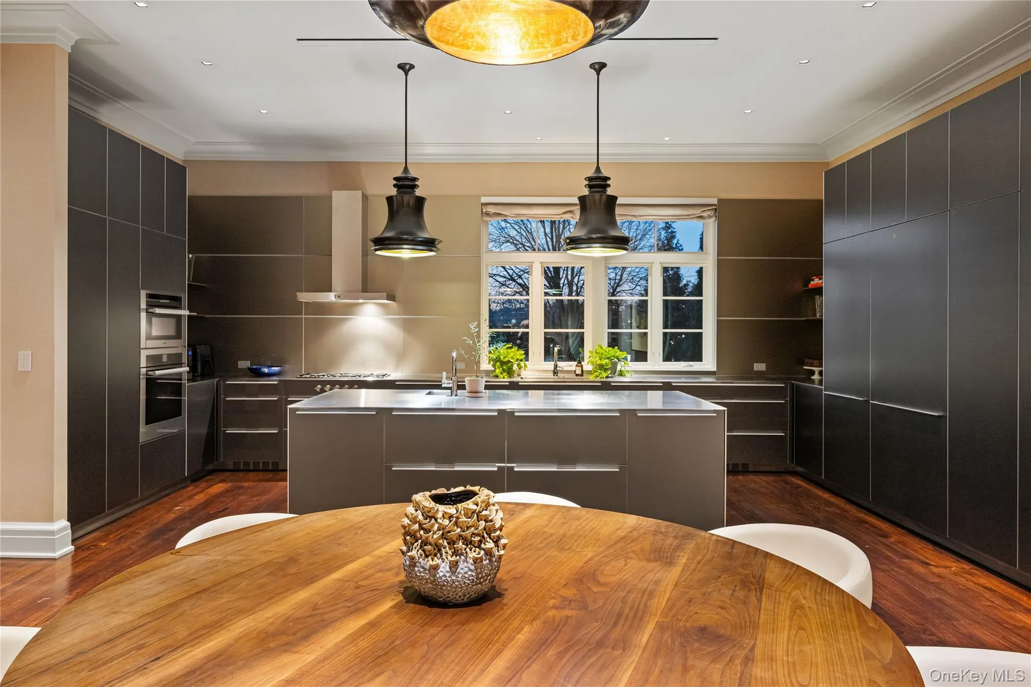 Kitchen with a kitchen island with sink, modern cabinets, ornamental molding, hanging light fixtures, and recessed lighting Kitchen with a kitchen island with sink, modern cabinets, ornamental molding, hanging light fixtures, and recessed lighting