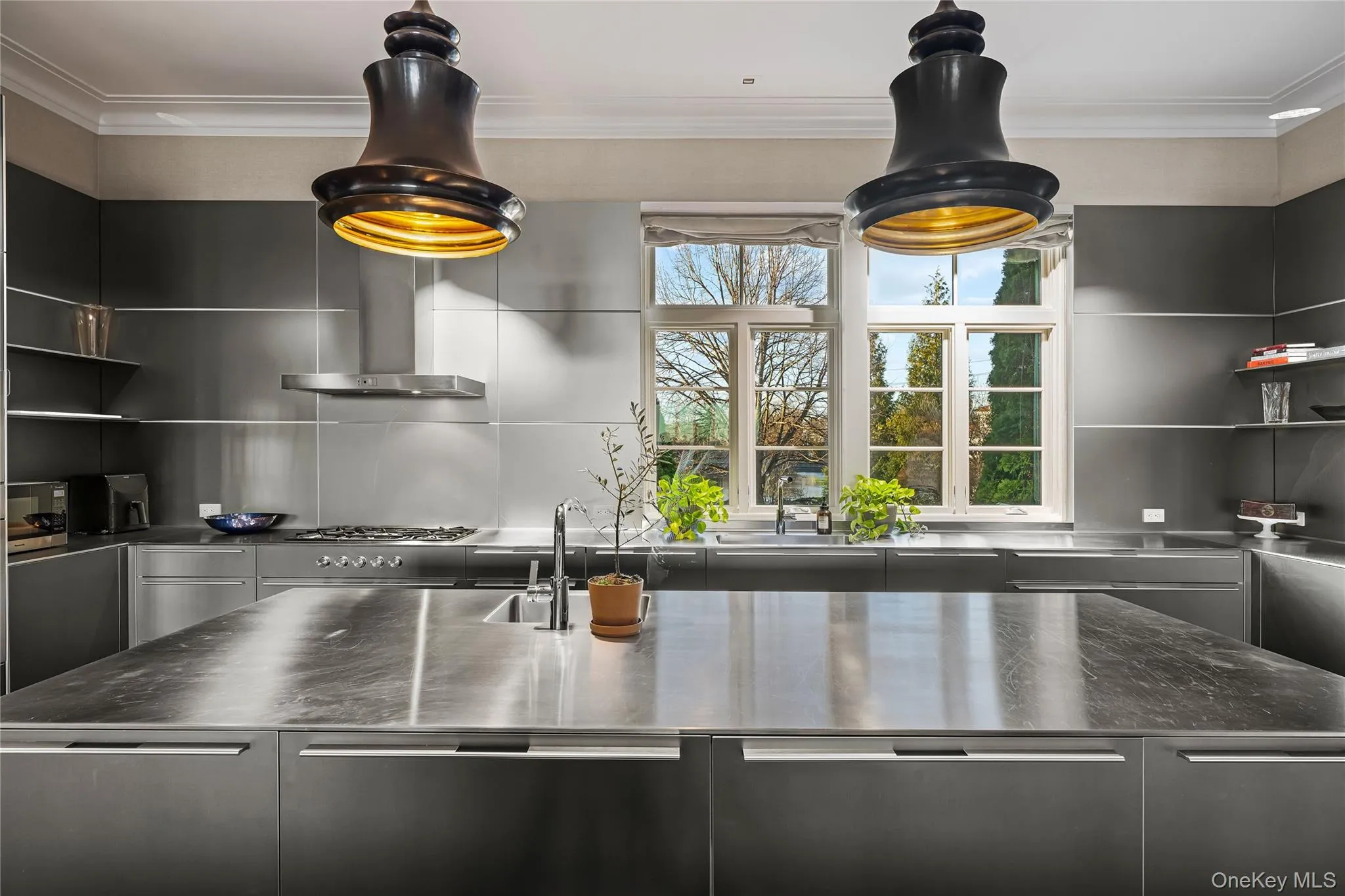 Kitchen featuring stainless steel counters, wall chimney exhaust hood, modern cabinets, and crown molding Kitchen featuring stainless steel counters, wall chimney exhaust hood, modern cabinets, and crown molding