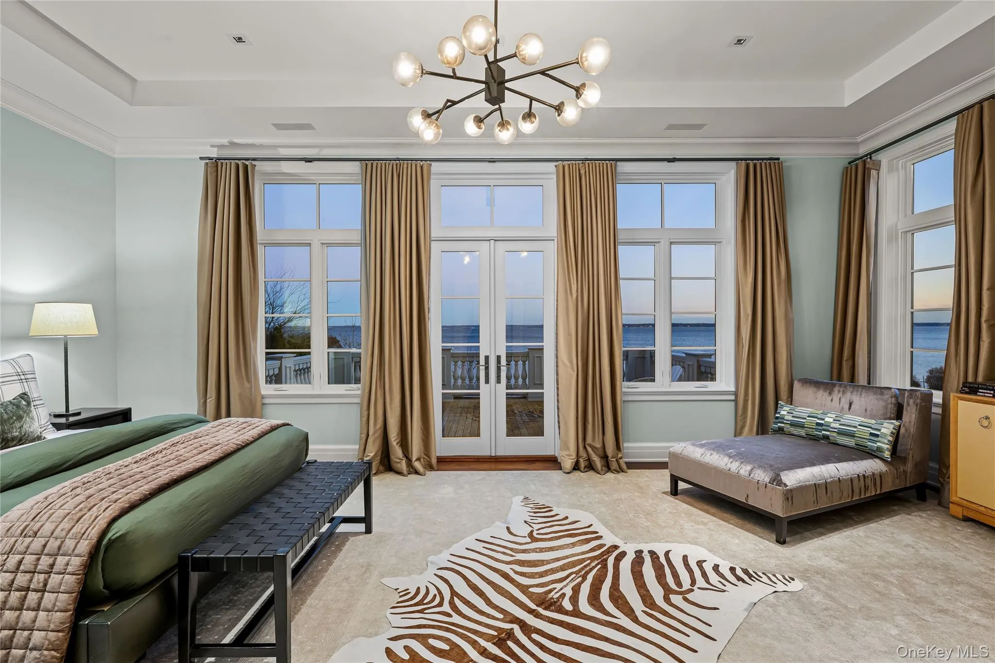 Bedroom featuring a water view, french doors, a tray ceiling, a chandelier, and carpet flooring Bedroom featuring a water view, french doors, a tray ceiling, a chandelier, and carpet flooring