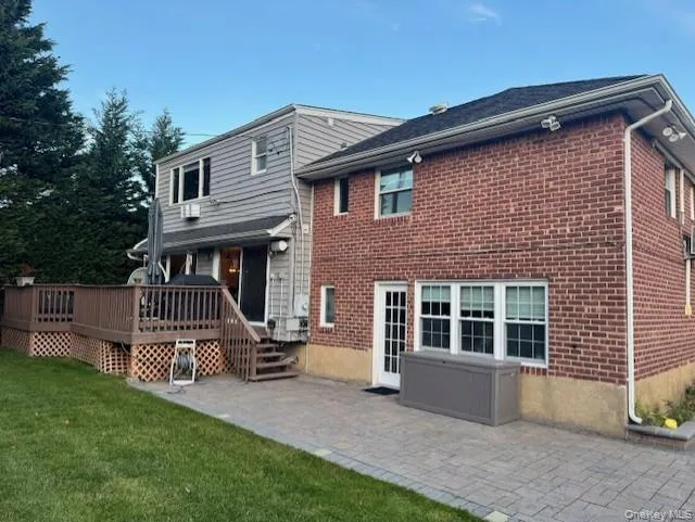 Rear view of house with brick siding, a lawn, a deck, and a patio Rear view of house with brick siding, a lawn, a deck, and a patio