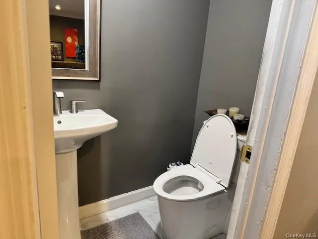 Half bathroom featuring light marble finish floors and baseboards Half bathroom featuring light marble finish floors and baseboards