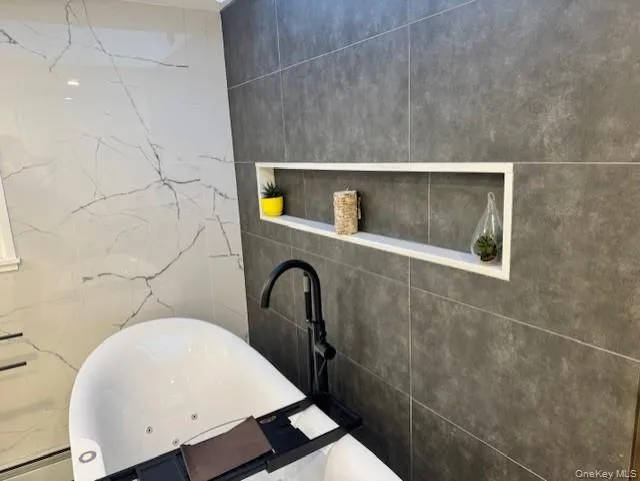 Full bathroom featuring tile walls and a soaking tub Full bathroom featuring tile walls and a soaking tub