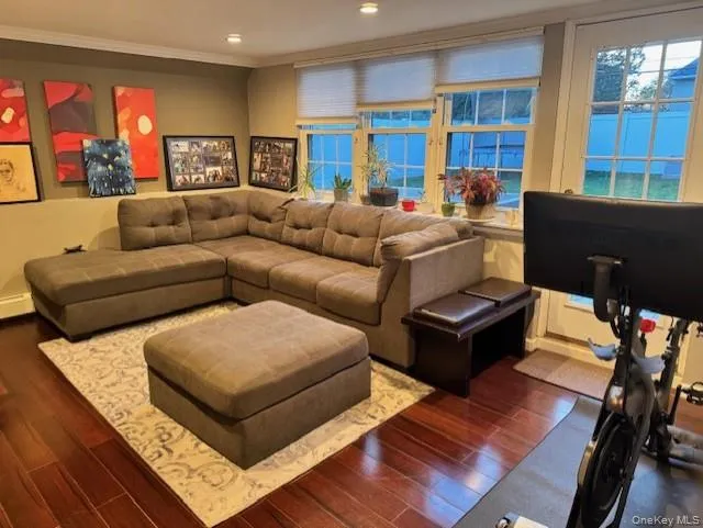 Living room with dark wood-style flooring, crown molding, healthy amount of natural light, and recessed lighting Living room with dark wood-style flooring, crown molding, healthy amount of natural light, and recessed lighting