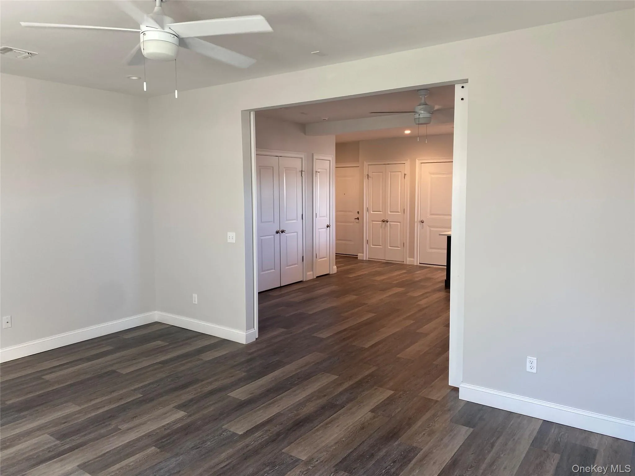 Empty room featuring dark wood-type flooring and a ceiling fan Empty room featuring dark wood-type flooring and a ceiling fan