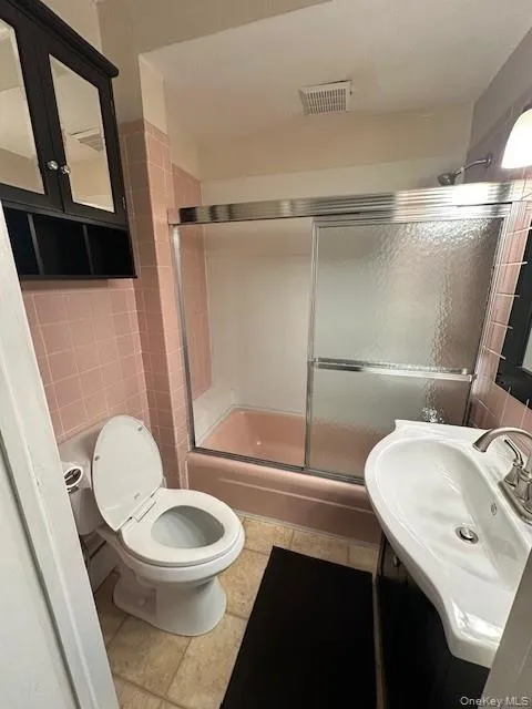 Full bathroom with tile walls, enclosed tub / shower combo, and vanity Full bathroom with tile walls, enclosed tub / shower combo, and vanity