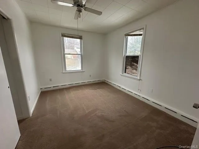 Spare room featuring carpet, a baseboard radiator, baseboard heating, and ceiling fan Spare room featuring carpet, a baseboard radiator, baseboard heating, and ceiling fan