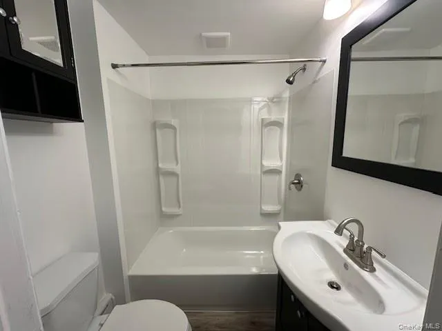 Bathroom featuring vanity, shower / bathtub combination, and dark wood-style flooring Bathroom featuring vanity, shower / bathtub combination, and dark wood-style flooring