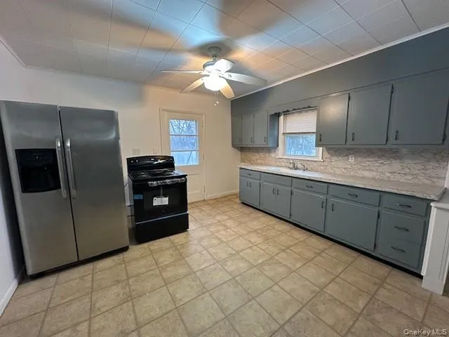 Kitchen featuring stainless steel fridge, gray cabinetry, black / electric stove, ceiling fan, and plenty of natural light Kitchen featuring stainless steel fridge, gray cabinetry, black / electric stove, ceiling fan, and plenty of natural light