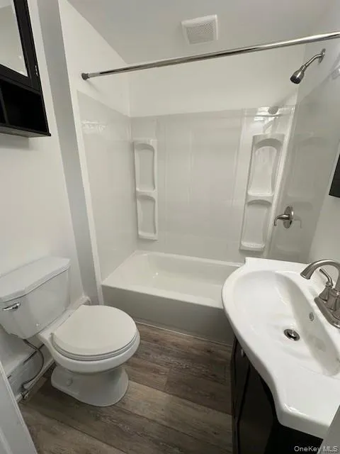 Full bathroom with dark wood finished floors, shower / bathtub combination, and vanity Full bathroom with dark wood finished floors, shower / bathtub combination, and vanity