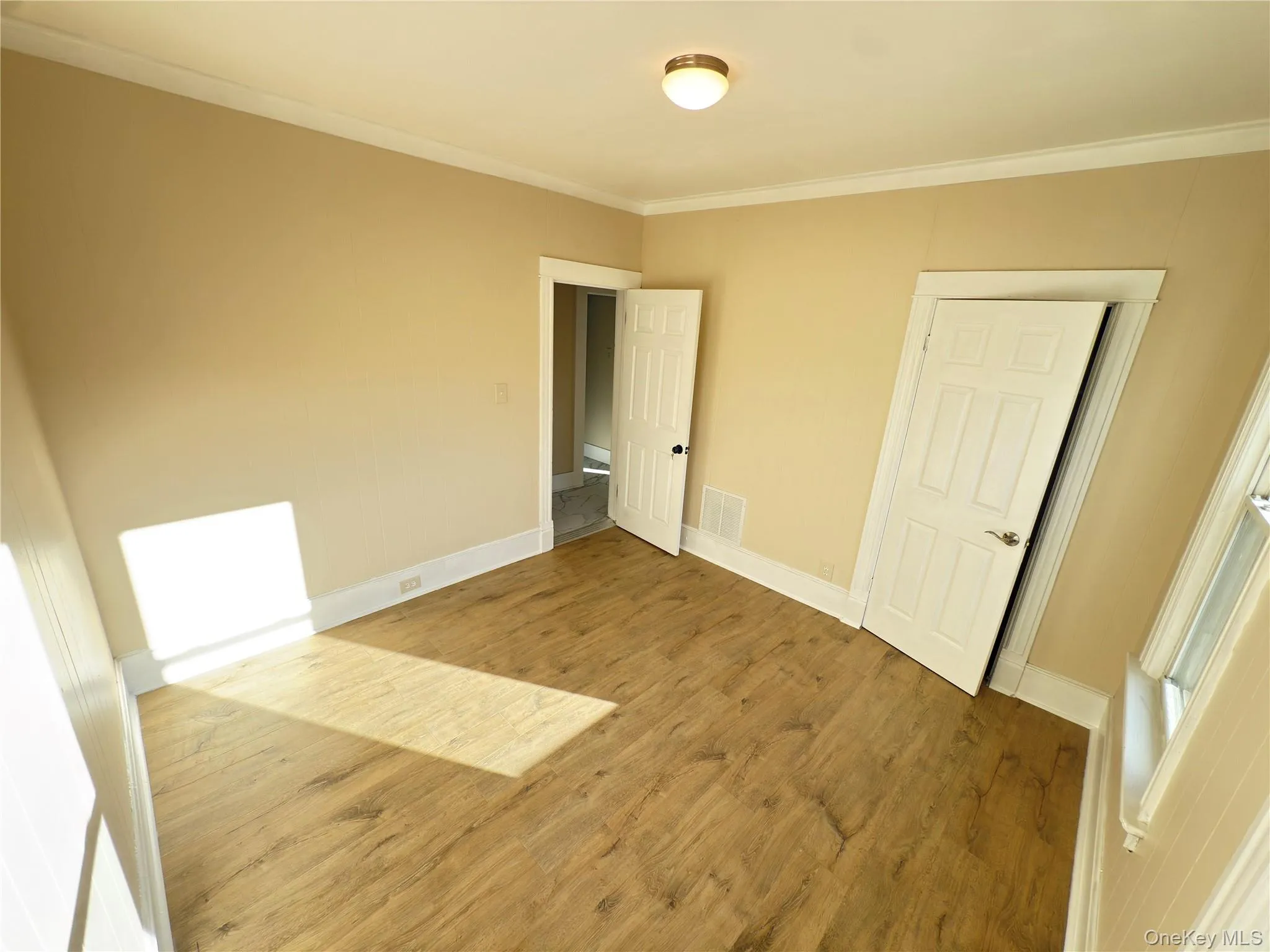 Unfurnished bedroom with wood finished floors and ornamental molding Unfurnished bedroom with wood finished floors and ornamental molding