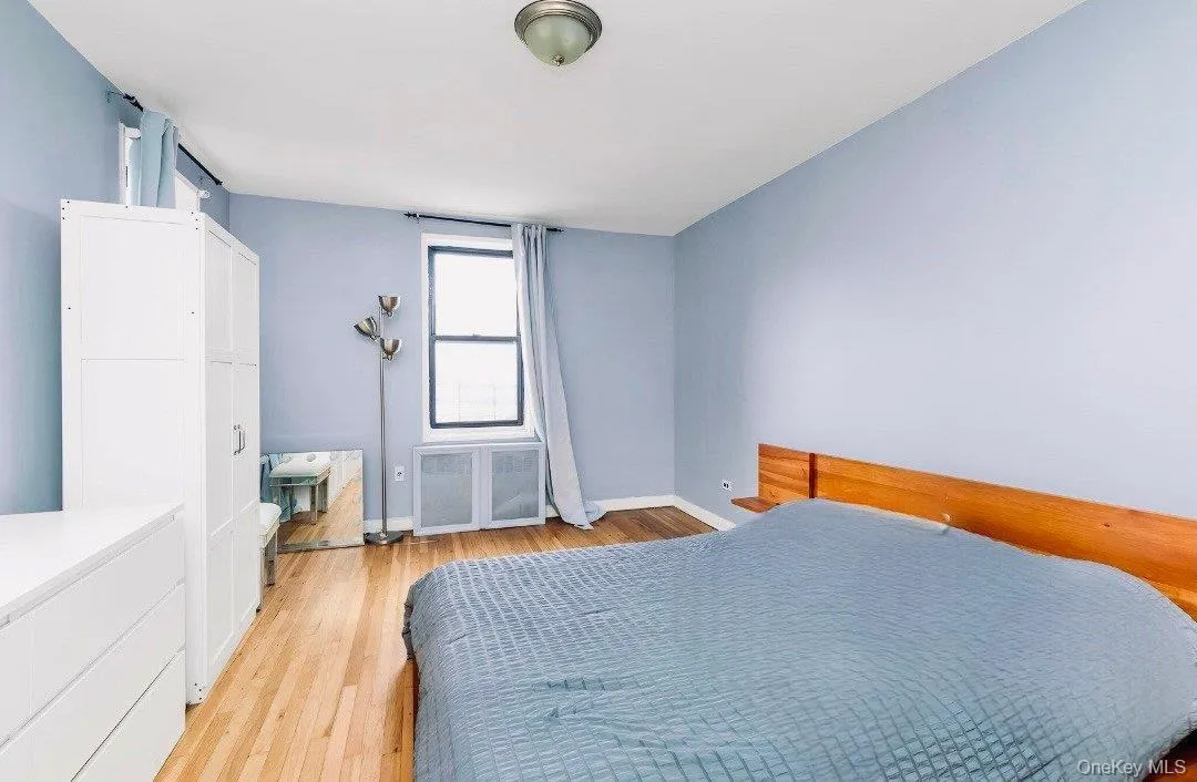 Bedroom featuring light wood-type flooring and radiator heating unit Bedroom featuring light wood-type flooring and radiator heating unit