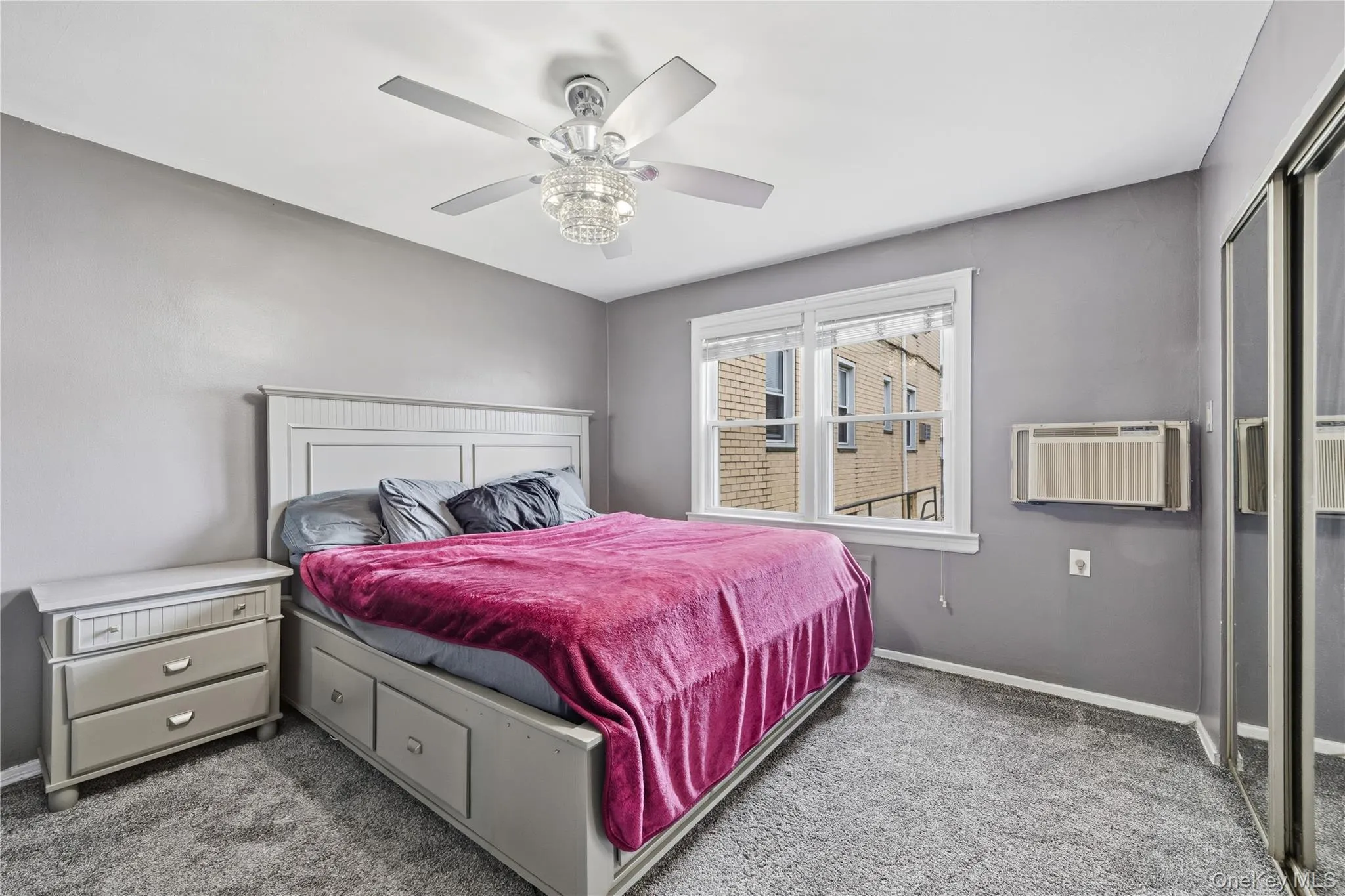 Carpeted bedroom featuring ceiling fan and a wall mounted AC Carpeted bedroom featuring ceiling fan and a wall mounted AC