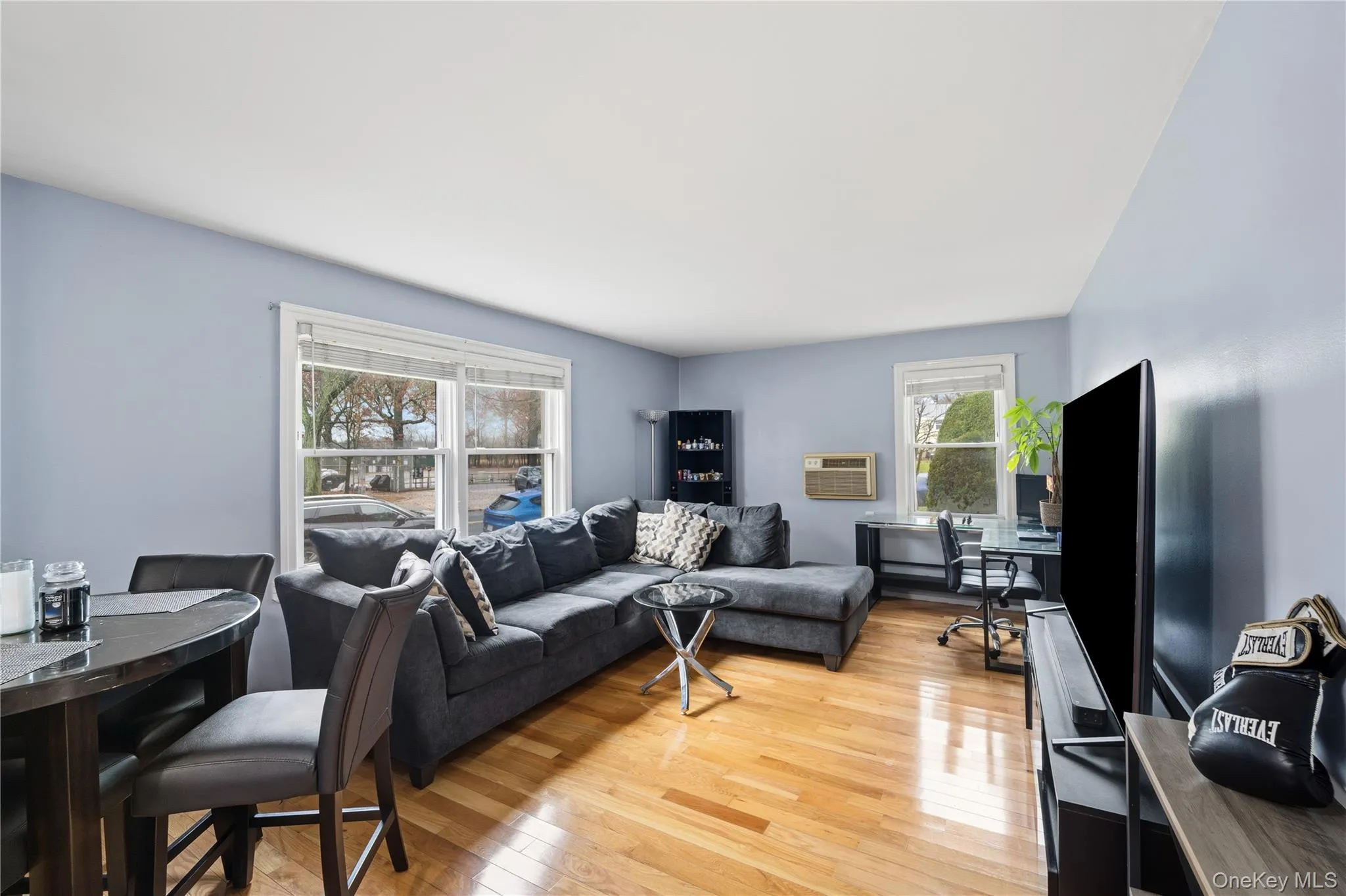 Living area with a desk, light wood-style floors, and a wall mounted air conditioner Living area with a desk, light wood-style floors, and a wall mounted air conditioner