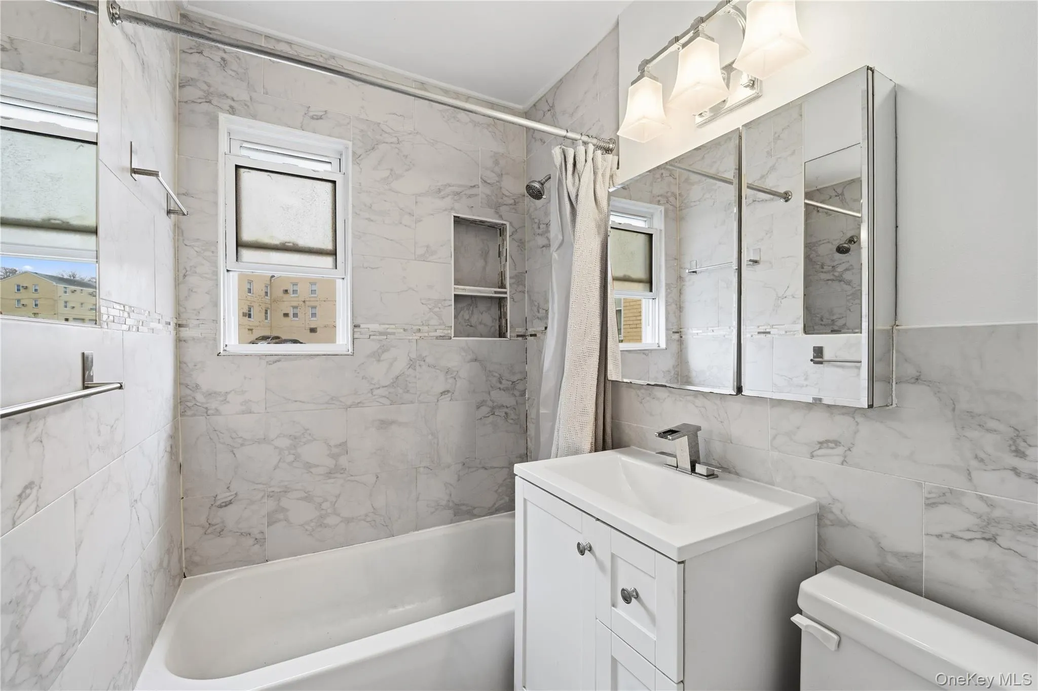Full bath featuring tile walls, healthy amount of natural light, shower / tub combo with curtain, and vanity Full bath featuring tile walls, healthy amount of natural light, shower / tub combo with curtain, and vanity