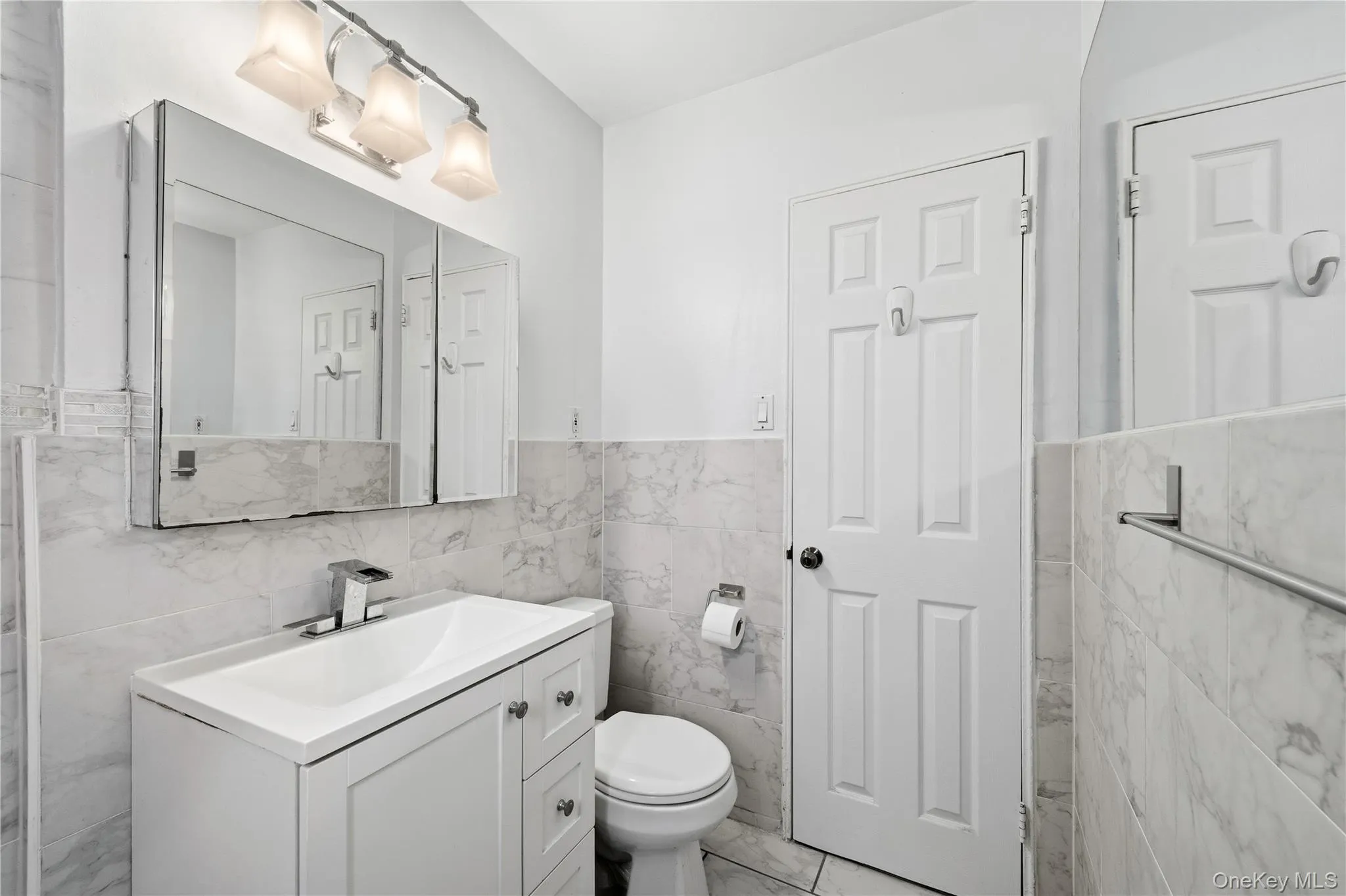 Bathroom featuring tile walls, vanity, and a wainscoted wall Bathroom featuring tile walls, vanity, and a wainscoted wall