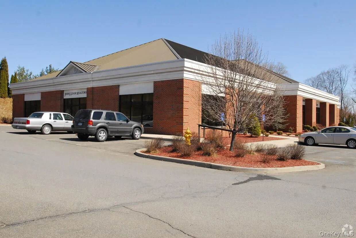 Brick facade building with a prominent peaked roof section and expansive front windows Brick facade building with a prominent peaked roof section and expansive front windows