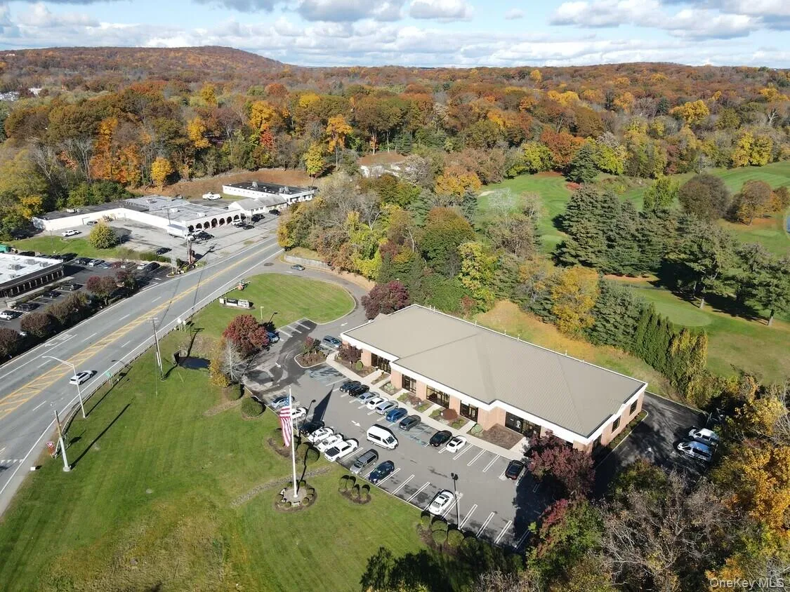 Commercial property featuring a brick exterior and a large surface parking lot Commercial property featuring a brick exterior and a large surface parking lot