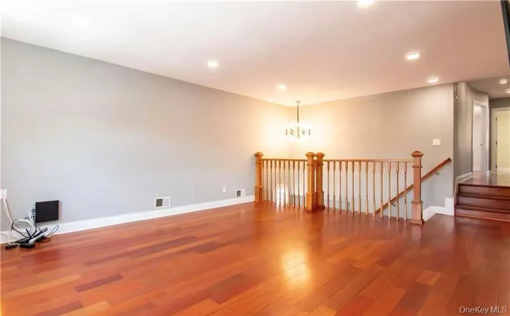 Unfurnished room with a chandelier, dark wood finished floors, recessed lighting, and stairway Unfurnished room with a chandelier, dark wood finished floors, recessed lighting, and stairway