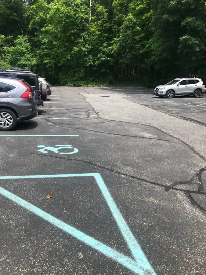 Uncovered parking lot featuring a view of trees Uncovered parking lot featuring a view of trees