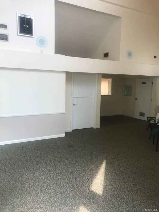 Unfurnished room with high vaulted ceiling and baseboards Unfurnished room with high vaulted ceiling and baseboards