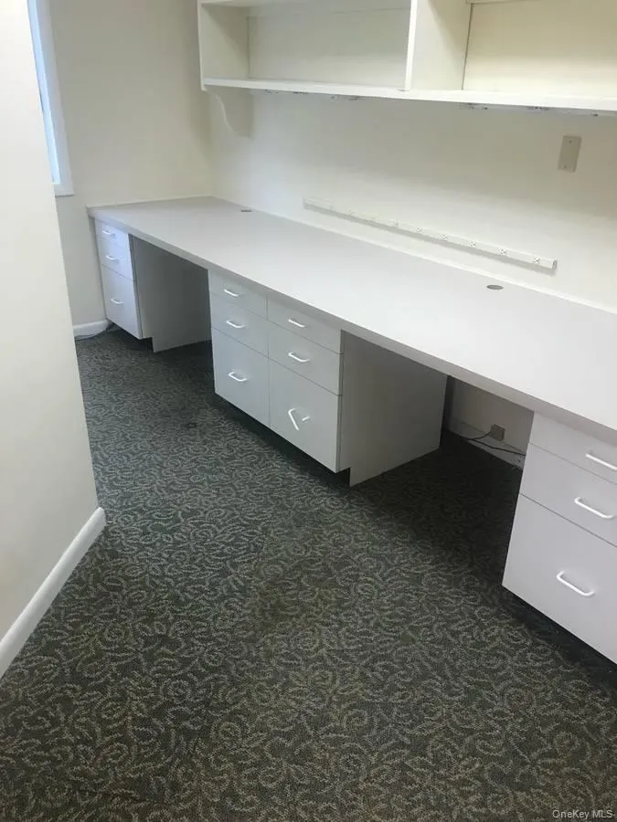Unfurnished office featuring built in desk and dark carpet Unfurnished office featuring built in desk and dark carpet