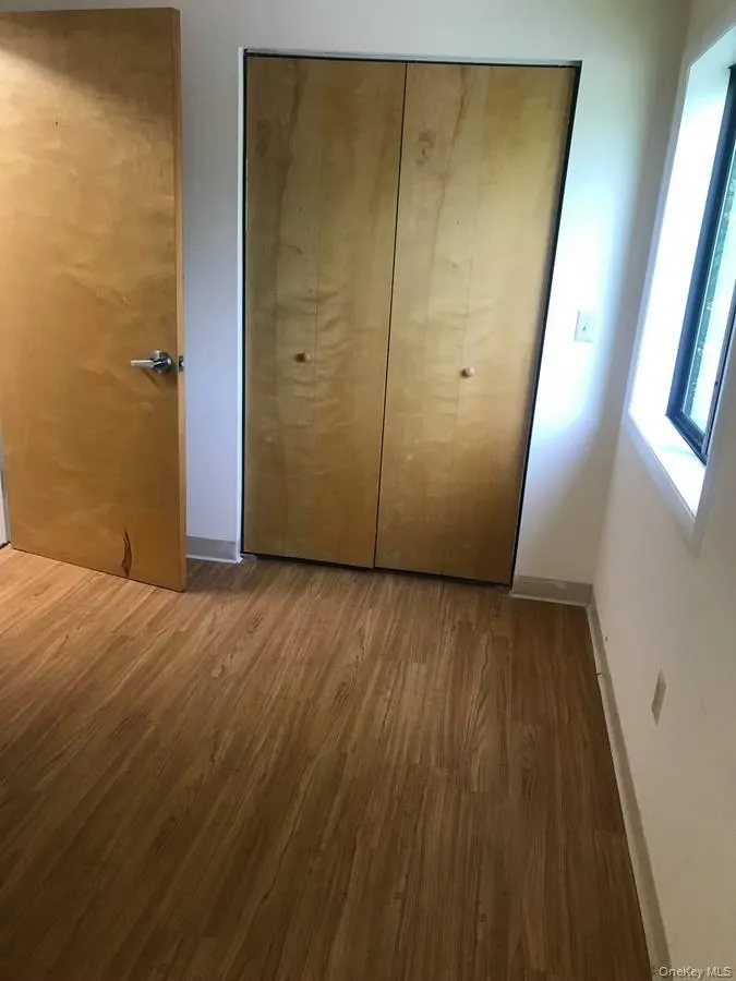 Unfurnished bedroom with wood finished floors and multiple closets Unfurnished bedroom with wood finished floors and multiple closets