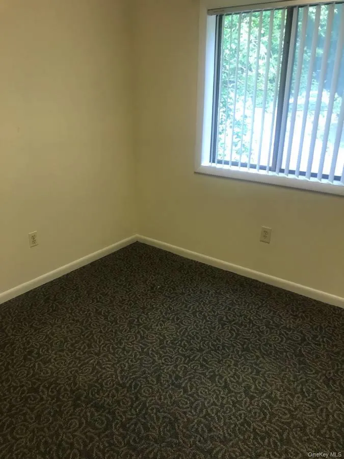 Empty room with baseboards and dark colored carpet Empty room with baseboards and dark colored carpet