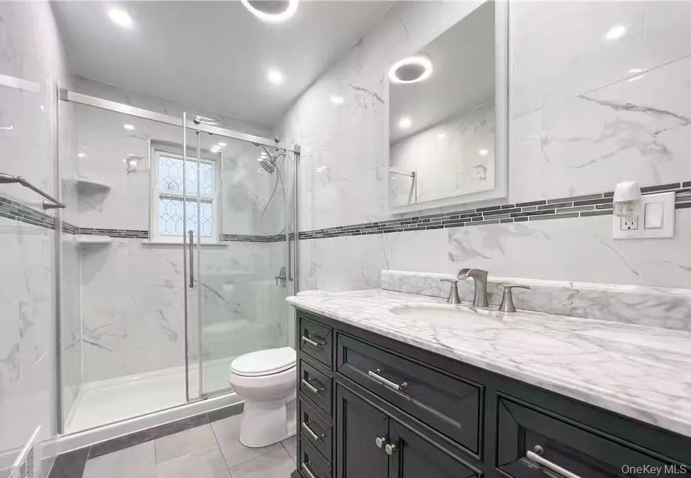 Bathroom featuring vanity, a marble finish shower, and recessed lighting Bathroom featuring vanity, a marble finish shower, and recessed lighting