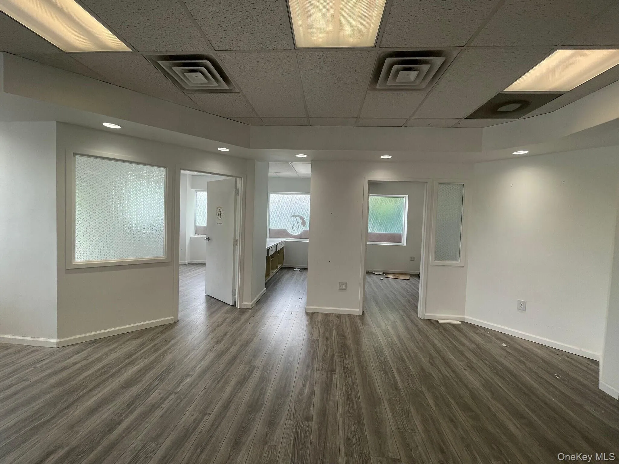 Unfurnished room featuring a drop ceiling and dark wood-style floors Unfurnished room featuring a drop ceiling and dark wood-style floors