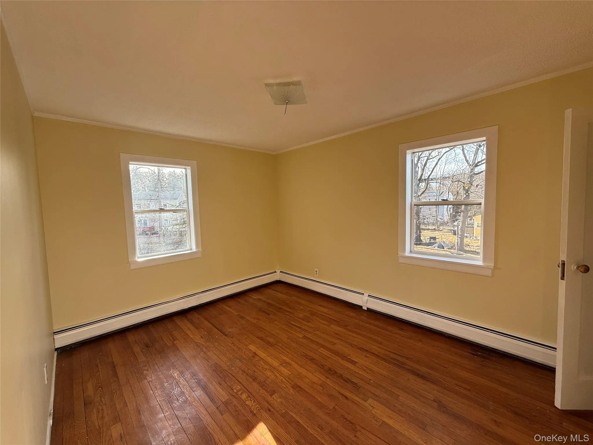 Spare room featuring plenty of natural light, dark wood finished floors, and ornamental molding Spare room featuring plenty of natural light, dark wood finished floors, and ornamental molding