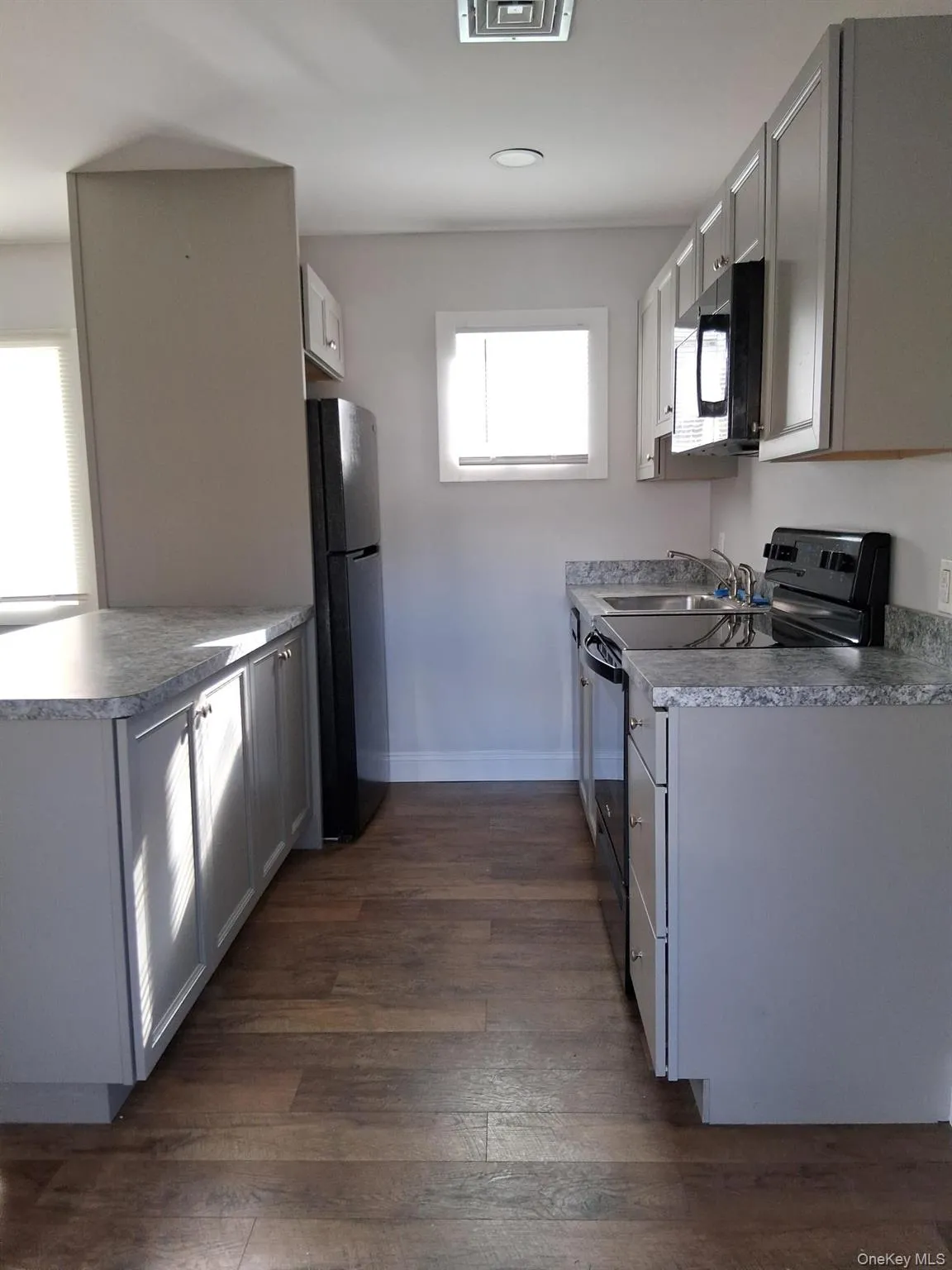 Kitchen with black appliances, dark wood-style flooring, gray cabinets, and a peninsula Kitchen with black appliances, dark wood-style flooring, gray cabinets, and a peninsula