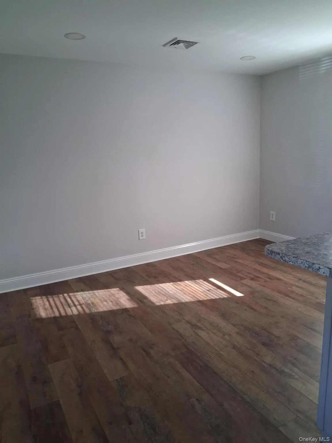 Spare room with dark wood-style flooring and baseboards Spare room with dark wood-style flooring and baseboards