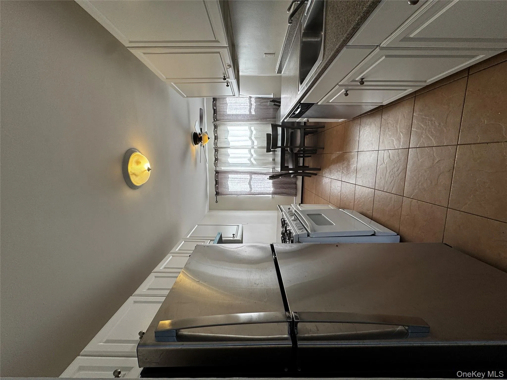 Kitchen featuring appliances with stainless steel finishes, white cabinetry, dark countertops, and a ceiling fan Kitchen featuring appliances with stainless steel finishes, white cabinetry, dark countertops, and a ceiling fan