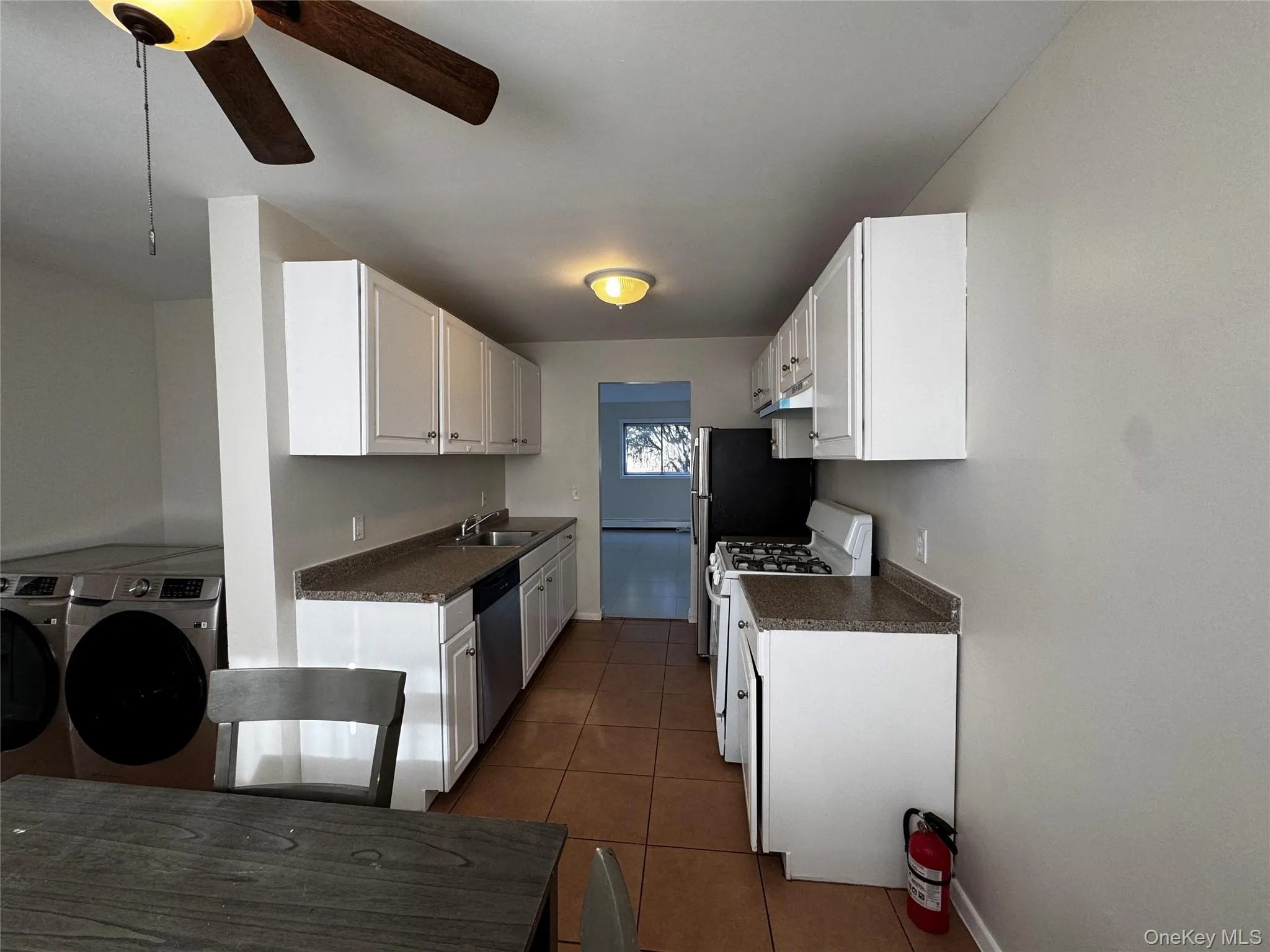 Kitchen with white cabinetry, white range with gas cooktop, dark countertops, and washing machine and clothes dryer Kitchen with white cabinetry, white range with gas cooktop, dark countertops, and washing machine and clothes dryer