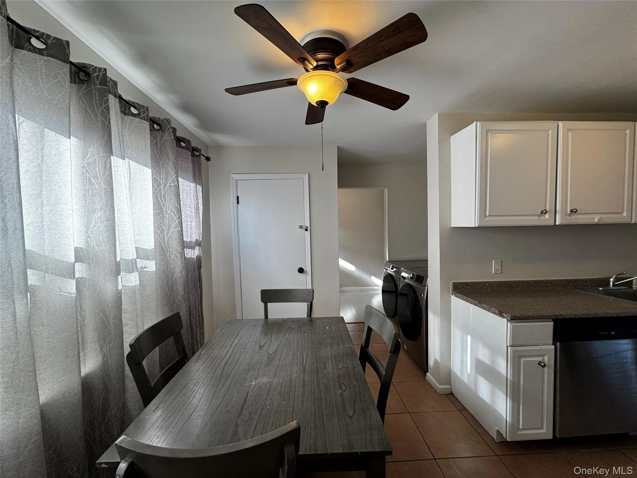 Dining room with dark tile patterned floors and washing machine and dryer Dining room with dark tile patterned floors and washing machine and dryer