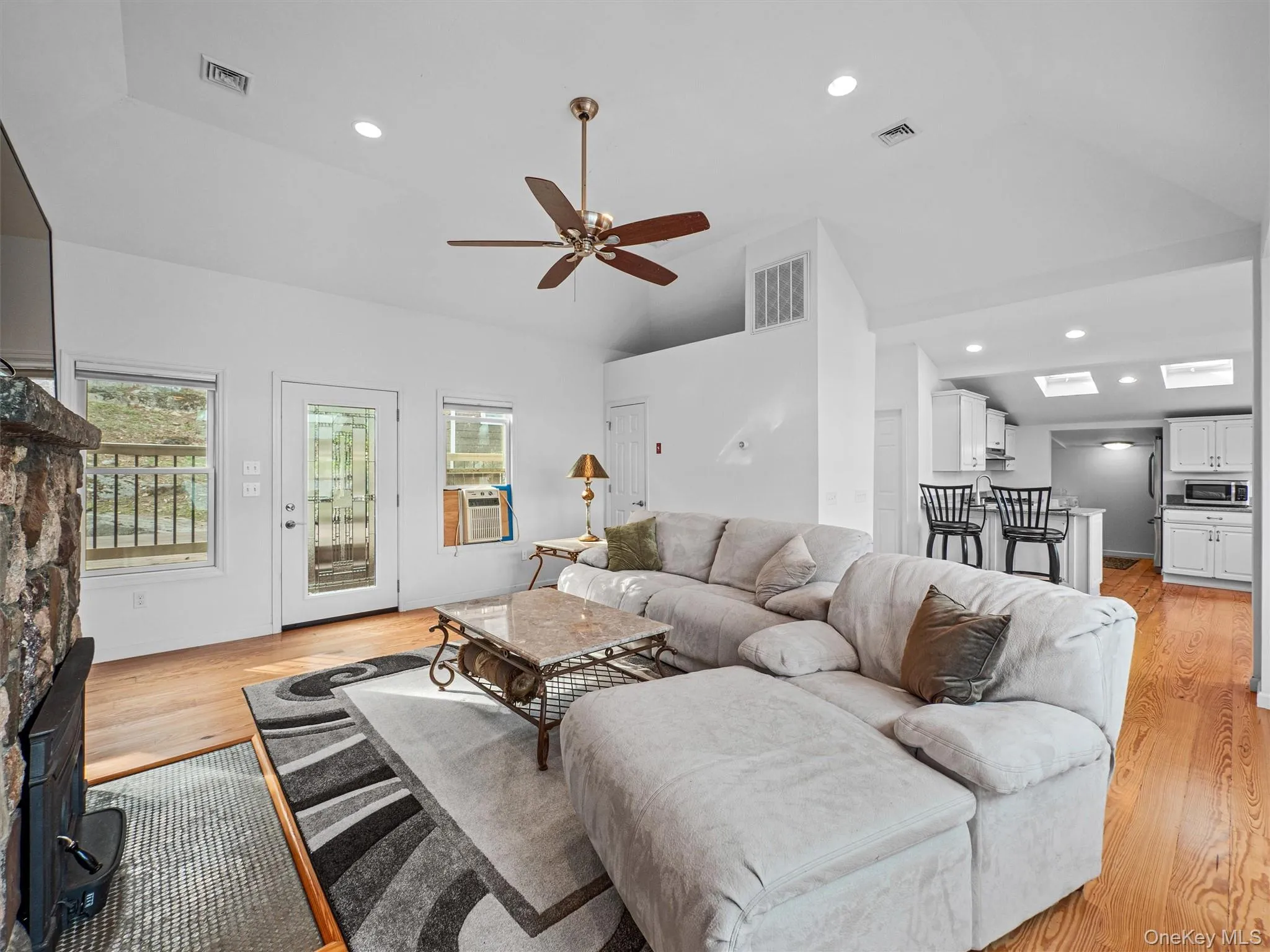 Living room featuring light wood finished floors, recessed lighting, a ceiling fan, healthy amount of natural light, and vaulted ceiling Living room featuring light wood finished floors, recessed lighting, a ceiling fan, healthy amount of natural light, and vaulted ceiling