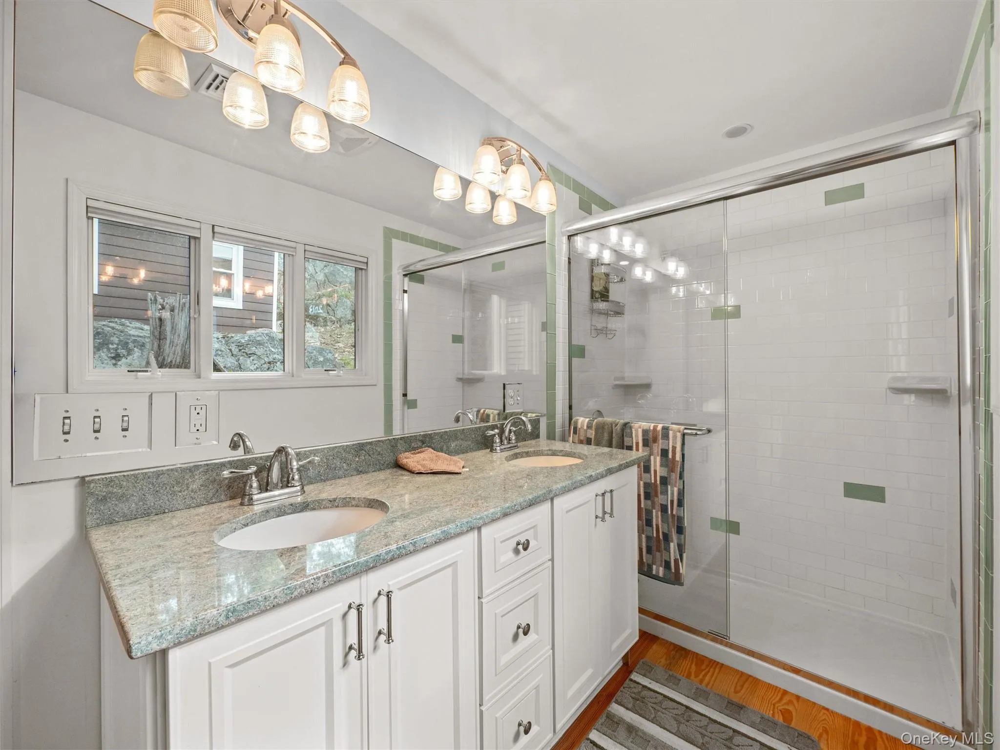 Full bathroom with double vanity, a stall shower, and light wood-style floors Full bathroom with double vanity, a stall shower, and light wood-style floors