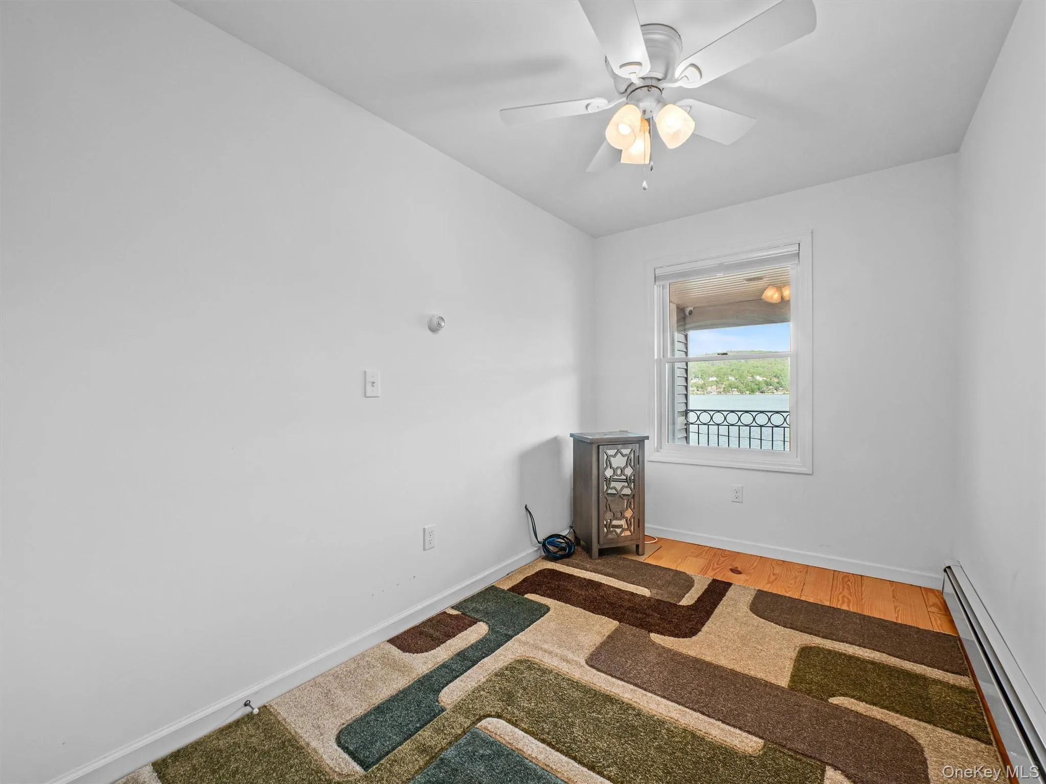Unfurnished room featuring a baseboard radiator, light wood-style floors, and a ceiling fan Unfurnished room featuring a baseboard radiator, light wood-style floors, and a ceiling fan