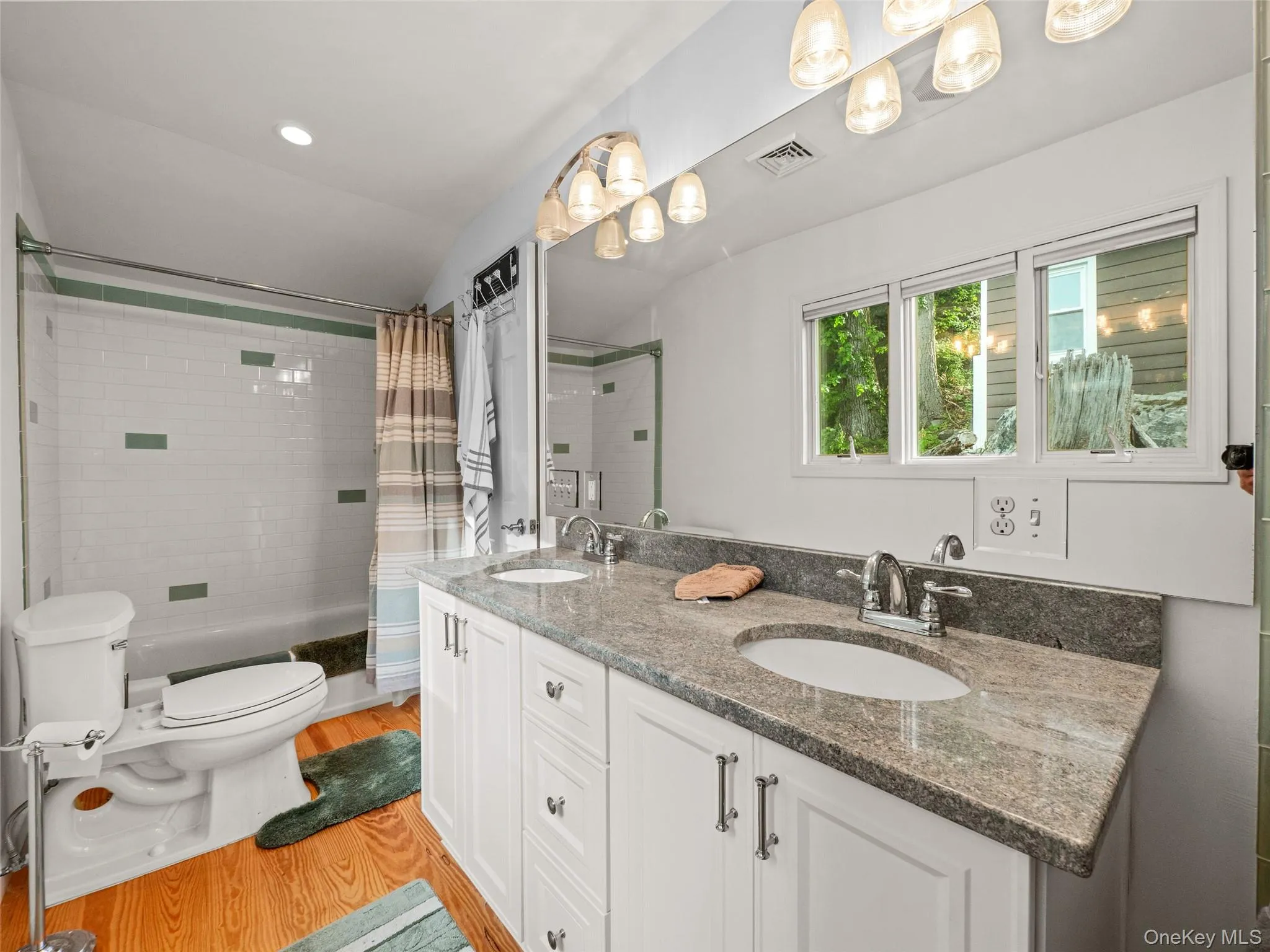 Full bath featuring double vanity, shower / tub combo with curtain, lofted ceiling, light wood finished floors, and recessed lighting Full bath featuring double vanity, shower / tub combo with curtain, lofted ceiling, light wood finished floors, and recessed lighting