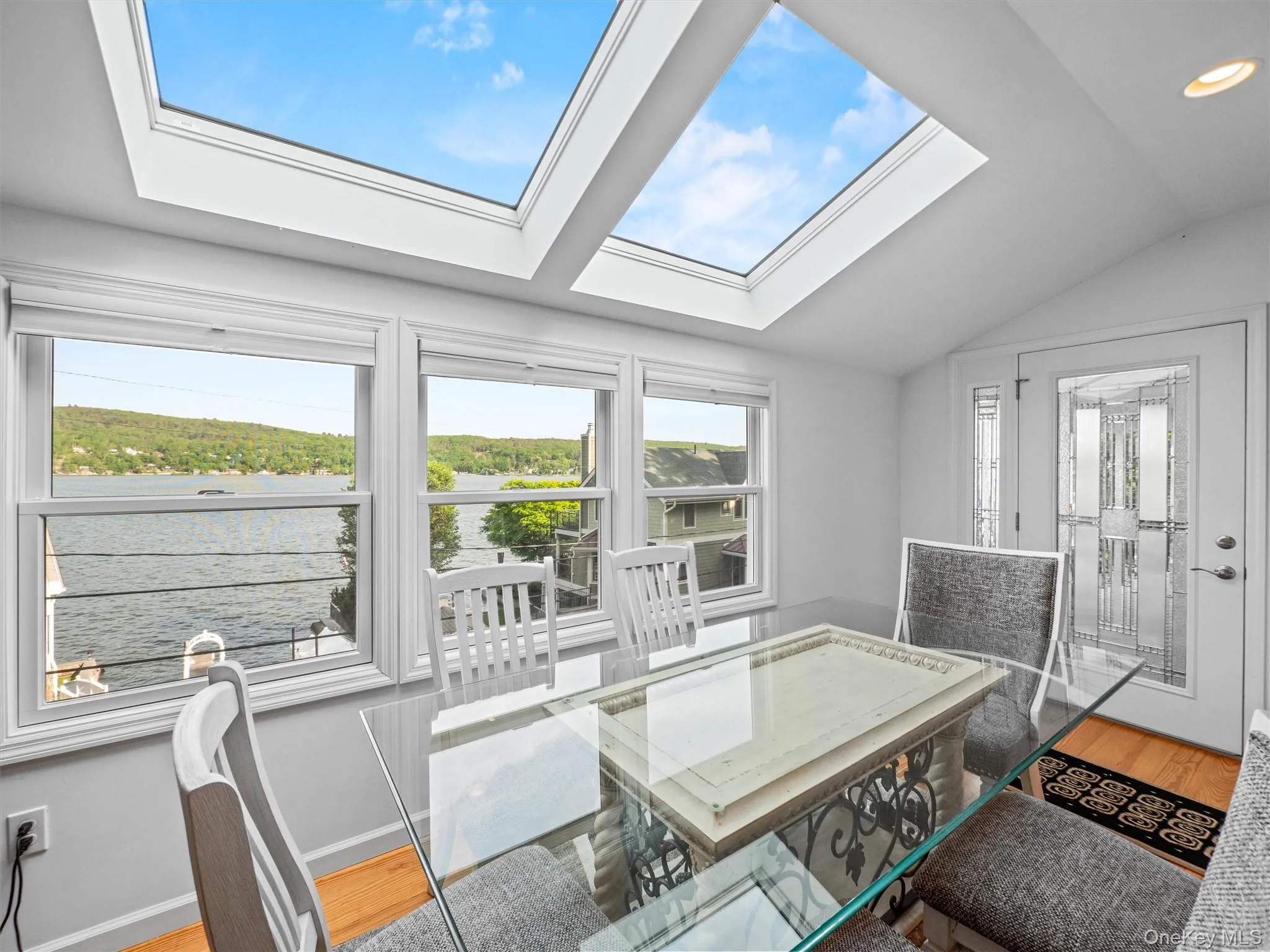 Dining room featuring a water view, lofted ceiling, and wood finished floors Dining room featuring a water view, lofted ceiling, and wood finished floors