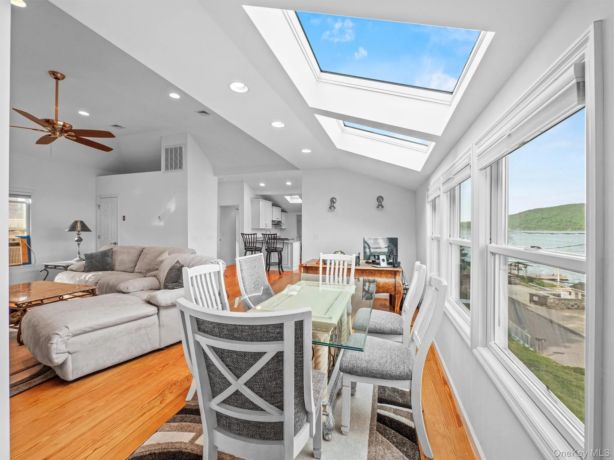 Dining room featuring vaulted ceiling, light wood-style flooring, a skylight, recessed lighting, and a water view Dining room featuring vaulted ceiling, light wood-style flooring, a skylight, recessed lighting, and a water view