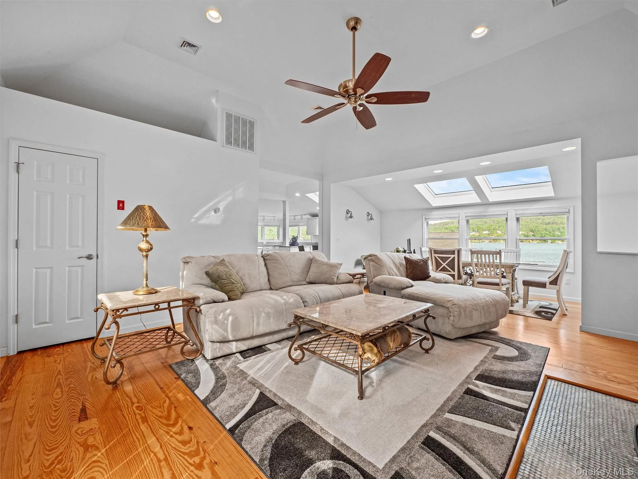 Living area with light wood-style floors, a skylight, ceiling fan, recessed lighting, and high vaulted ceiling Living area with light wood-style floors, a skylight, ceiling fan, recessed lighting, and high vaulted ceiling