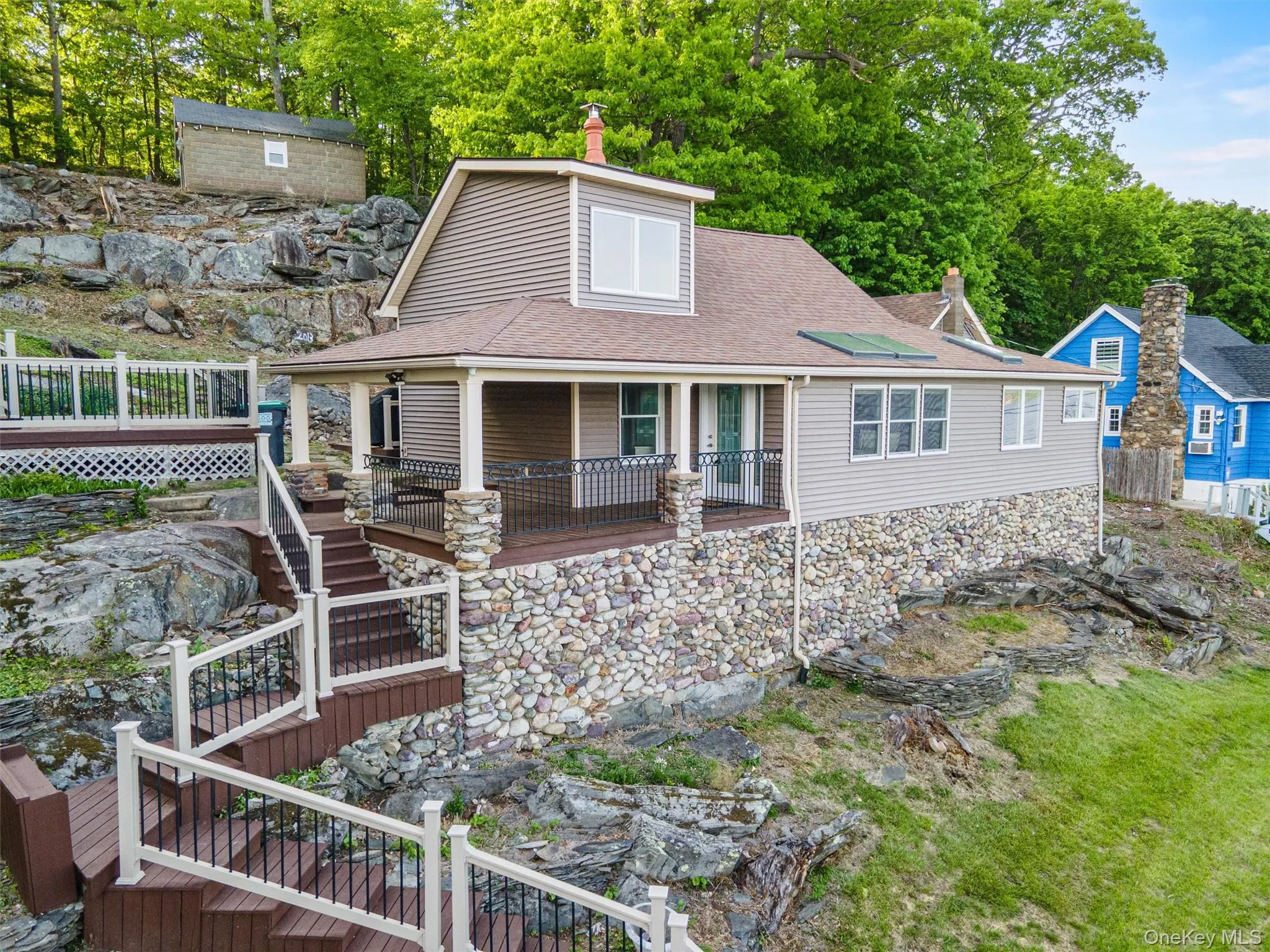 View of front of property featuring stairway, a shingled roof, a wooden deck, a chimney, and stone siding View of front of property featuring stairway, a shingled roof, a wooden deck, a chimney, and stone siding