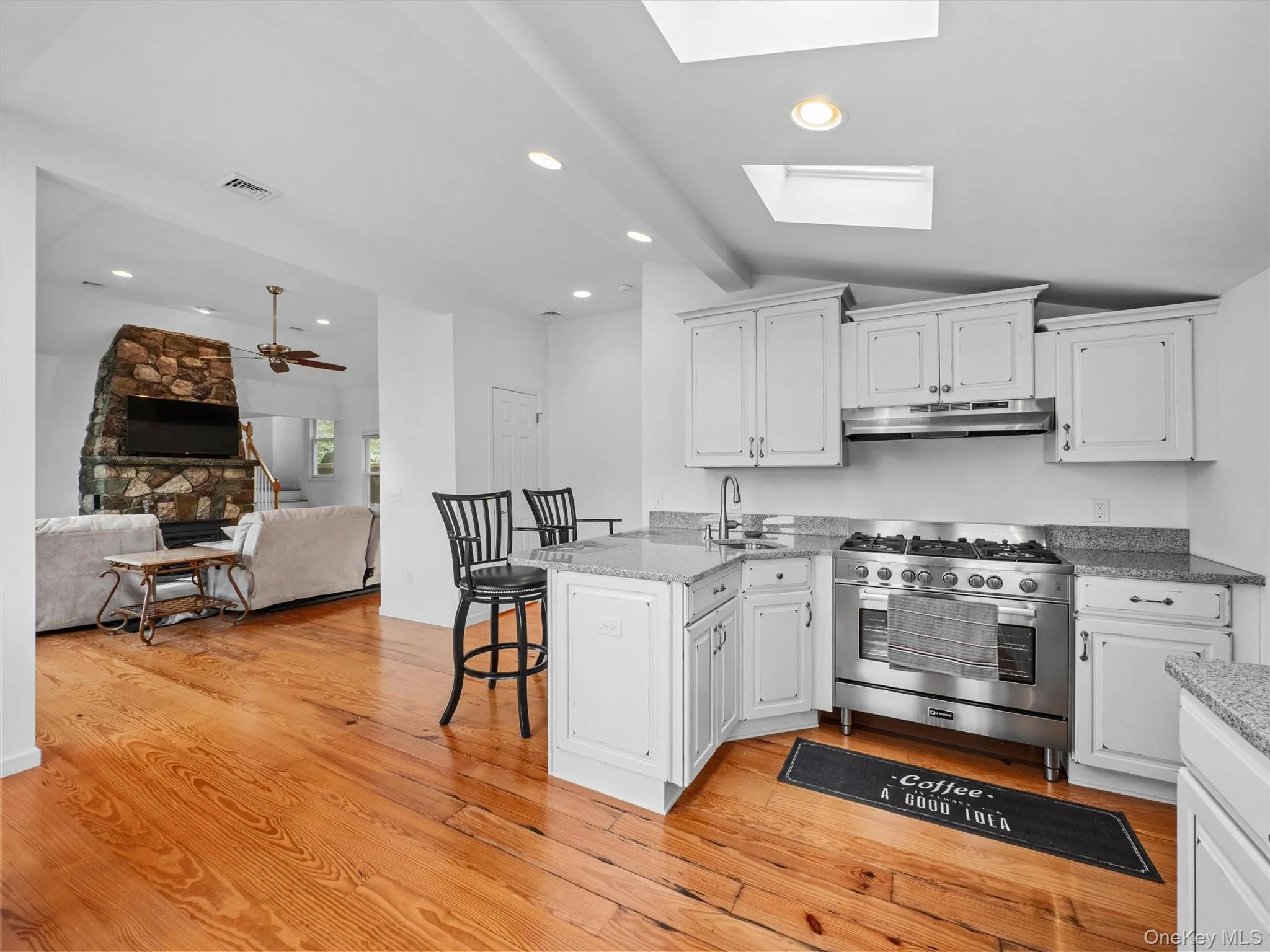 Kitchen with a peninsula, stainless steel gas range, a breakfast bar, white cabinets, and open floor plan Kitchen with a peninsula, stainless steel gas range, a breakfast bar, white cabinets, and open floor plan