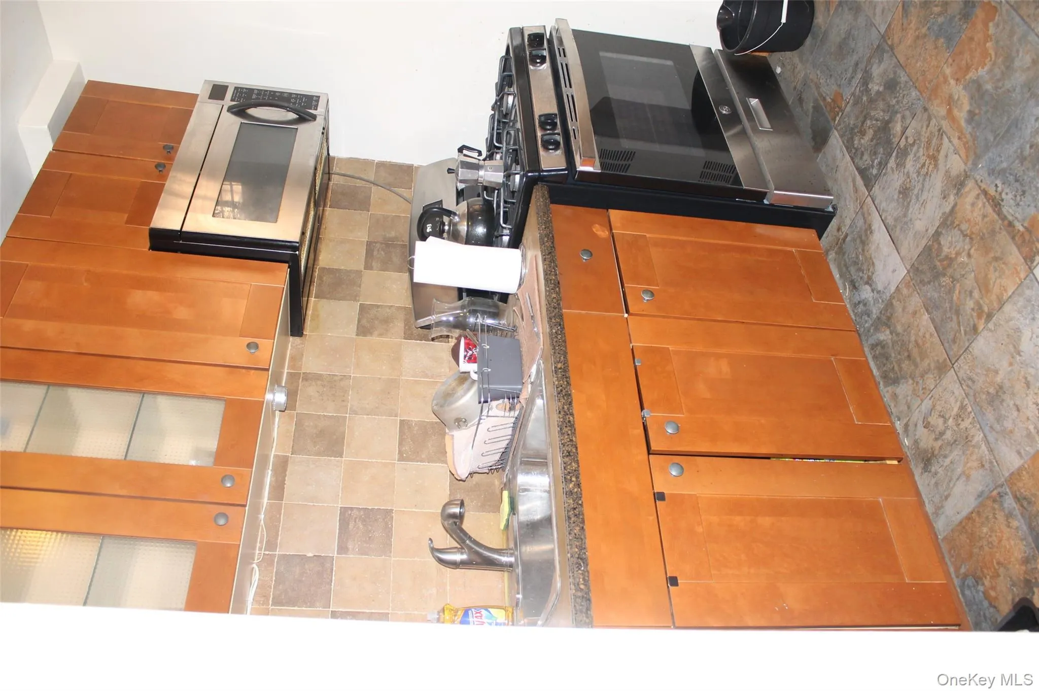 Kitchen featuring range, brown cabinets, dark countertops, and decorative backsplash Kitchen featuring range, brown cabinets, dark countertops, and decorative backsplash
