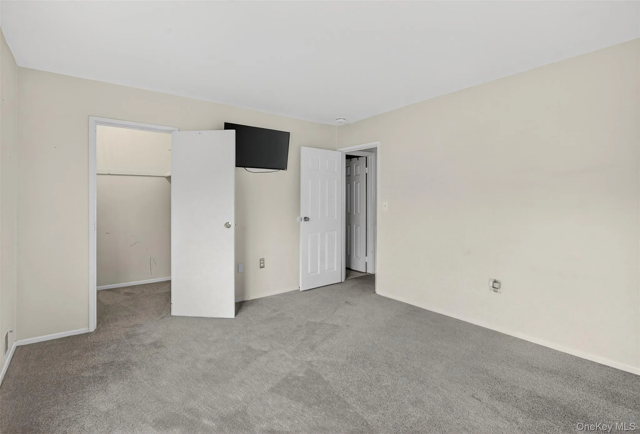 Unfurnished bedroom with carpet and a spacious closet Unfurnished bedroom with carpet and a spacious closet