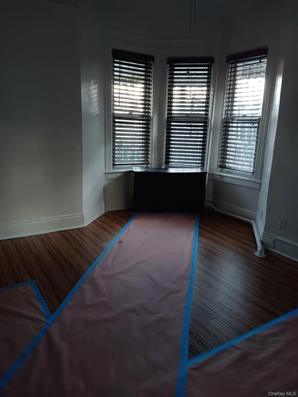 Unfurnished bedroom with dark wood finished floors and a baseboard heating unit Unfurnished bedroom with dark wood finished floors and a baseboard heating unit